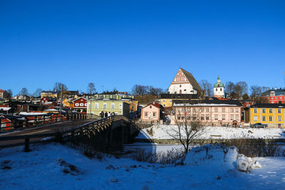 Snow covered houses and buildings against clear blue sky