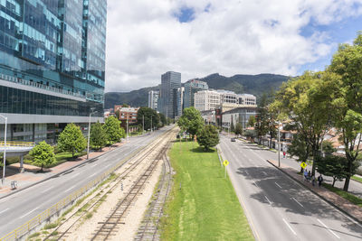 Road amidst buildings in city against sky