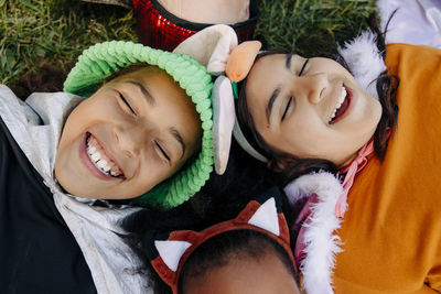 Carefree kids with eyes closed laughing while lying on grass at summer camp