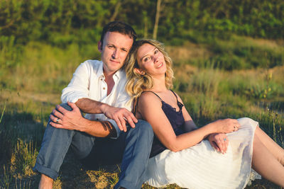 Portrait of young couple sitting on field