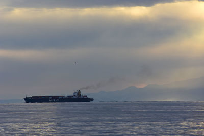 Ship sailing on sea against sky during sunset