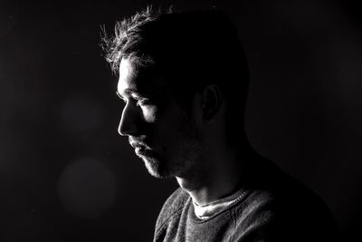 Profile view of man with stubble over black background