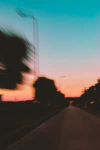 Blurred motion of car on street against sky at sunset