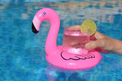 Cropped hand holding drink on inflatable ring in swimming pool