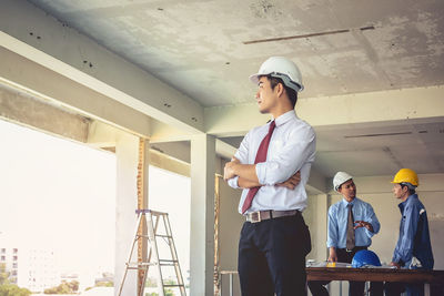 Confident engineer with colleagues standing at construction site