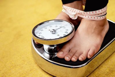 Close-up of woman standing on weighing scale