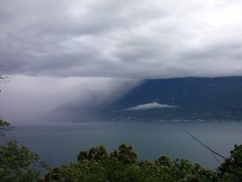 Scenic view of sea and mountains against cloudy sky