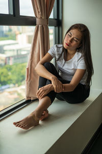 Portrait of woman sitting by window at home