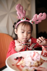 A little girl in santa red costume eating cake at cafe