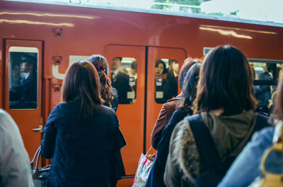 Rear view of people standing on train in city