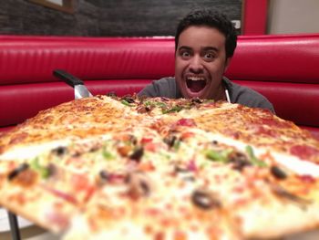 Portrait of man with mouth open by pizza at restaurant