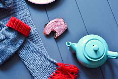 Close-up of blue teapot by sweater on table