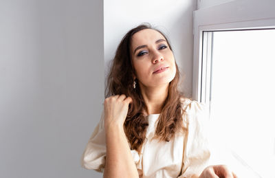 Portrait of smiling young woman looking away against wall