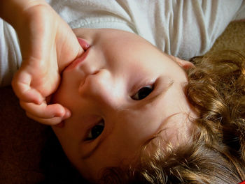 Close-up portrait of cute girl lying on bed at home