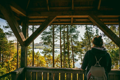 Rear view of woman standing in gazebo against trees