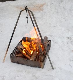 Close-up of firewood burning in fire pit on snow