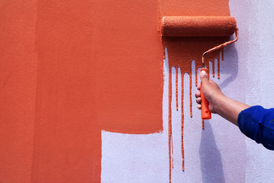 Midsection of man holding orange wall