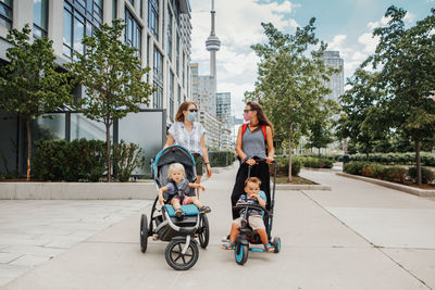 Two moms with strollers and kids walking together. women in face masks with children outdoor