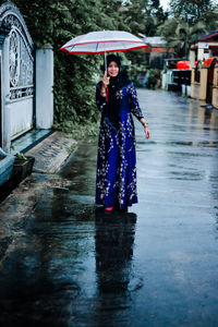 Rear view of woman with umbrella walking on street