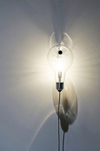 Illuminated light bulb against wall