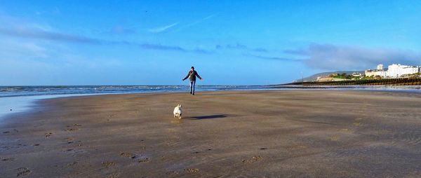 Man with dog at beach against sky