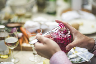 Cropped image of man removing pickle from jar at table during dinner party