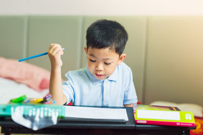 Boy looking at camera while sitting on table at home