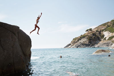 Woman jumping into sea