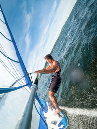 Wide-angle shot of adult man windsurfing on lake wallersee, austria.