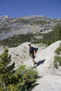 Man standing on rocky mountain against clear blue sky