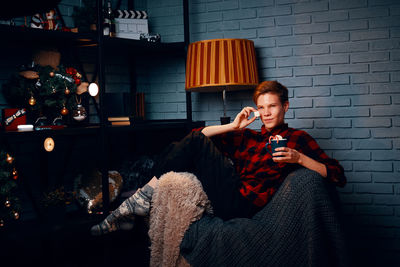 Young man using mobile phone while sitting on sofa