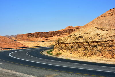 Road by mountain against clear blue sky