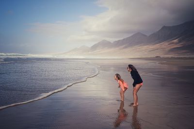 Friends enjoying at beach against sky