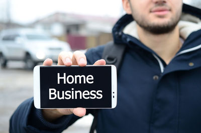 Man holding mobile phone with home business text