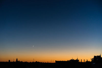 Silhouette city against clear sky during sunset