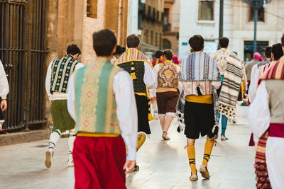 Rear view of people walking on street in city