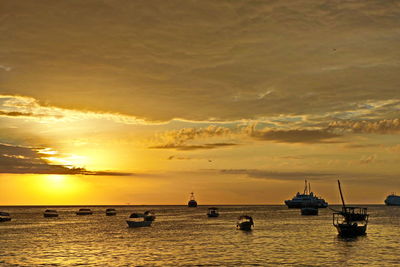 Silhouette boats in sea against sky during sunset