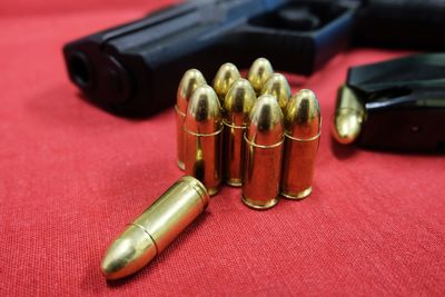 Close-up of gold bullets and handgun on table