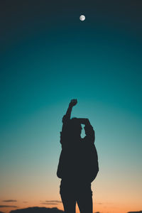 Rear view of silhouette  woman standing against moon at sunset