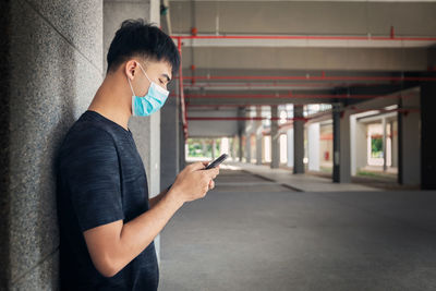 Side view of young man using mobile phone