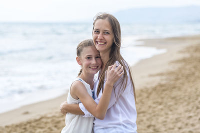 Portrait of mother with daughter standing at beach