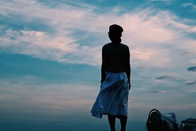 Rear view of woman standing against cloudy sky