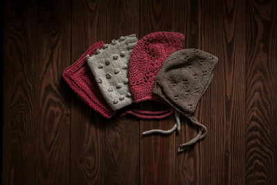 Children's knitted hats on a brown wooden background, autumn children's wardrobe and manual work