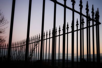 Low angle view of silhouette fence against clear sky