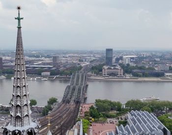 Aerial view of buildings in city against cloudy sky