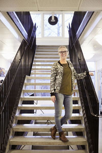 Full length portrait of teacher standing on steps of middle school