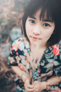 Close-up portrait of young woman holding plant