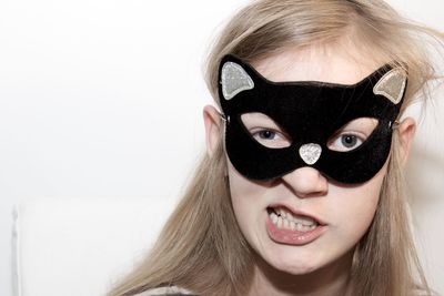 Portrait of girl wearing cat shape mask against white background