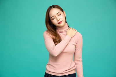 Young woman standing against blue background