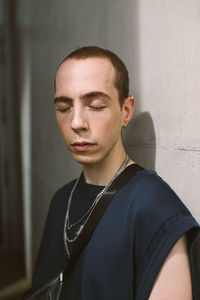 Portrait of young man standing against wall